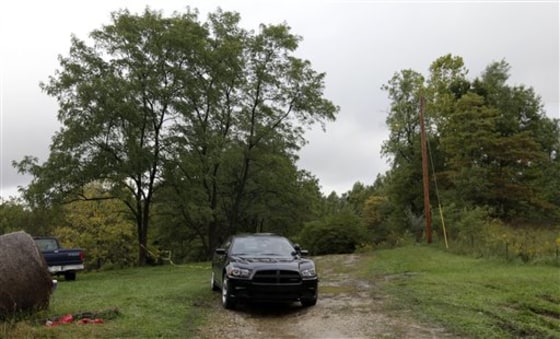 A police officer in an unmarked car guards the entrance to the site where five people were found dead in rural Franklin County near the town of Laurel, Ind., on Monday.